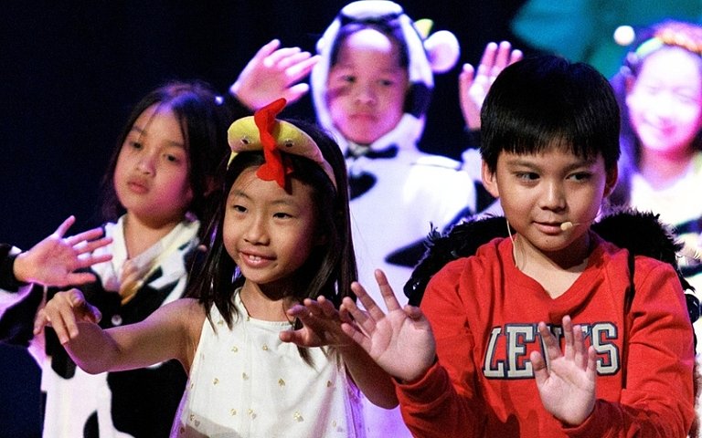  Year 3 and Year 4 pupils developing confidence through performing arts as part of a British curriculum education. 