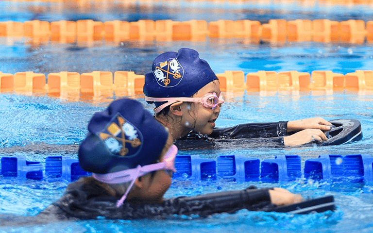  KS1 pupils showcasing their swimming abilities as part of a well-rounded British curriculum education. 
