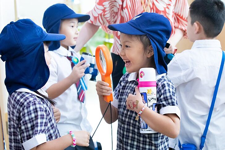  Pupils exploring the world through play with a magnifying glass at Brighton College Vibhavadi, encouraging curiosity in early learning. 