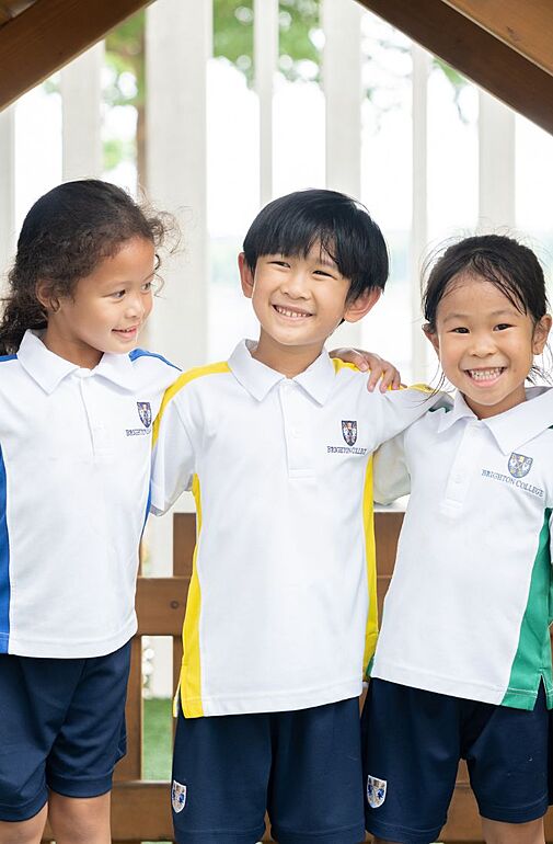  Three smiling pupils at the House Kid playground at Brighton College Vibhavadi Prep School, enjoying playtime in a safe and supportive space. 